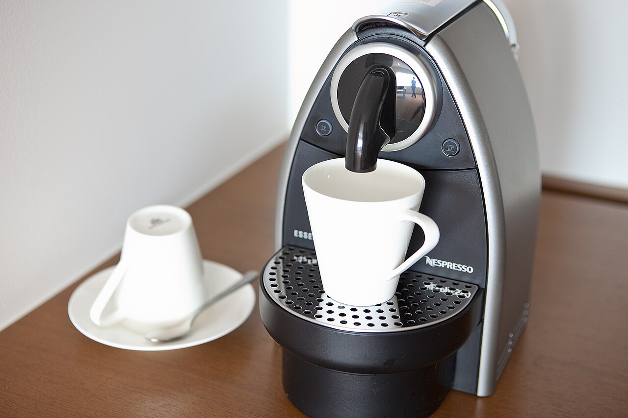 A Nespresso capsule coffee machine of the same general type dispensing coffee into a cup